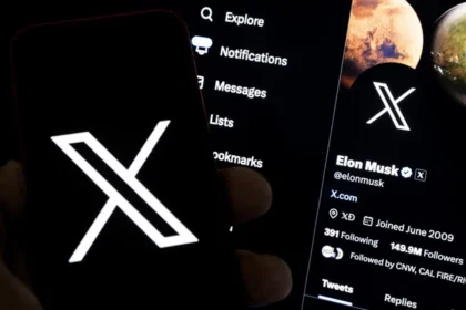 A smartphone displaying the X logo in front of a screen showing Elon Musk’s X profile, highlighting the sale of X to xAI for $45 billion.