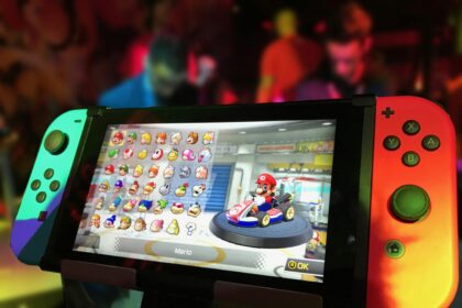 Nintendo Switch console displaying Mario Kart character selection screen, with neon-lit gaming event in the background.