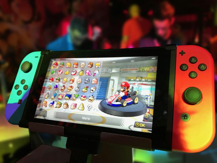 Nintendo Switch console displaying Mario Kart character selection screen, with neon-lit gaming event in the background.