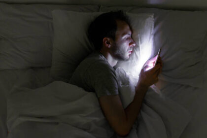 young man using phone in bed late at night