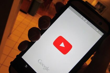 A person holding phone with YouTube app opening