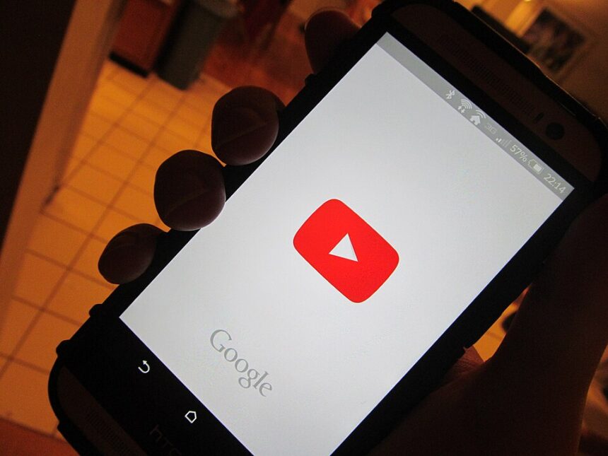 A person holding phone with YouTube app opening